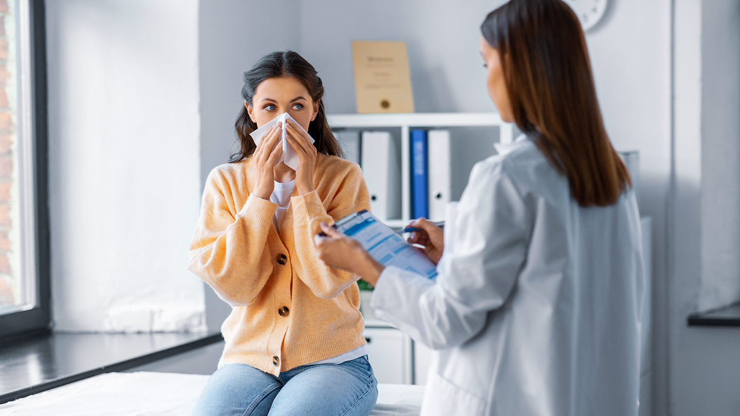 Žena s gripom koju pregleda ljekar.
