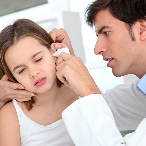 Djevojčica koju pregleda doktor zbog infekcije uha.