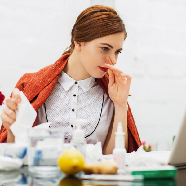 Bolesna žena sa prehladom u kancelariji.