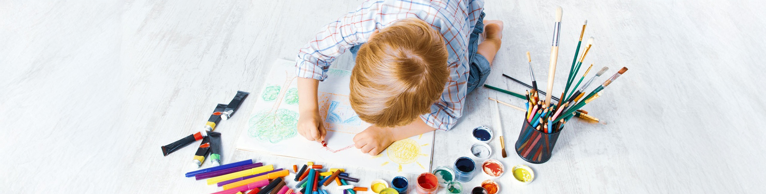 Dijete se igra bojicama na podu.
