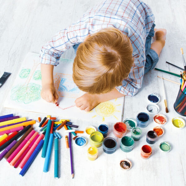 Dijete se igra bojicama na podu.
