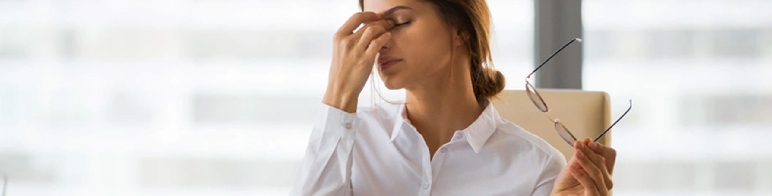 Umorna žena za stolom u kancelariji, stres, iscrpljenost.
