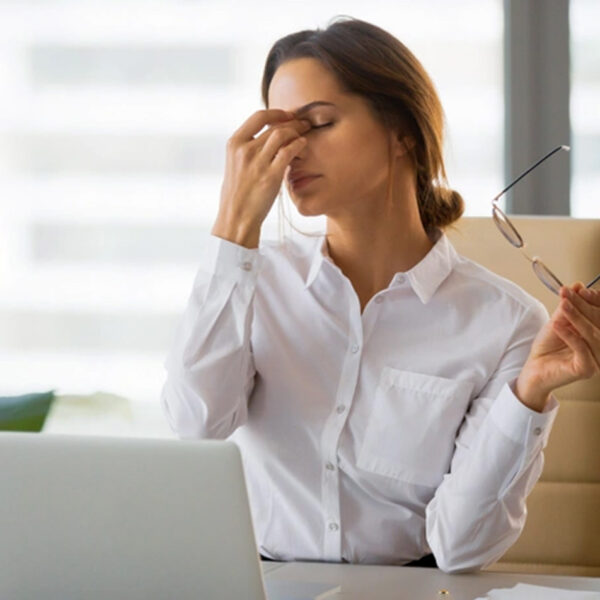 Umorna žena za stolom u kancelariji, stres, iscrpljenost.
